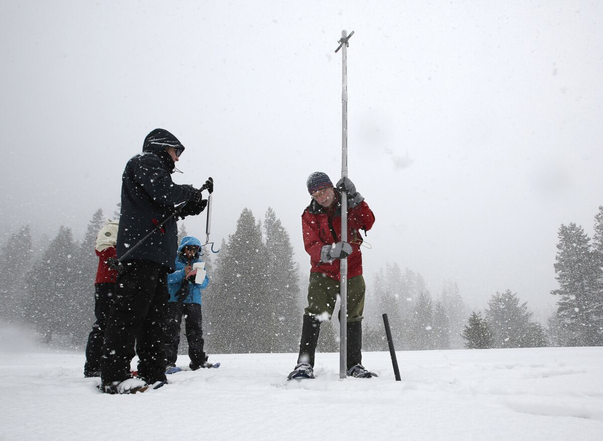 Frank Gehrke, right, chief snow surveyor for the Department of Water Resources, lifts his survey tube out of the snowpack at Phillips Station near Echo Summit, Calif. (Rich Pedroncelli / Associated Press)