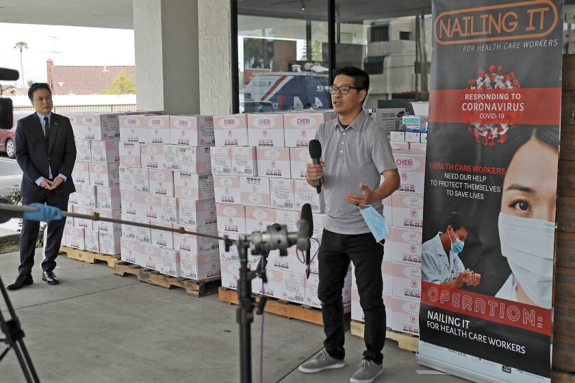 Tam Nguyen, Advance Beauty College president, right, and Johnny Ngo, Whale Spa Salon Furniture and Skyline Beauty Supply president, practice social distancing as they address the media at Whale Spa Salon Furniture in Huntington Beach on Tuesday, March 31. Those who want to donate can drop-off supplies at two collection centers setup at Advance Beauty College's locations in Garden Grove and Laguna Hills.