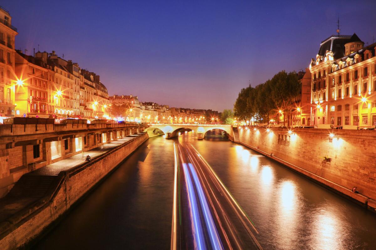 Light trails of a boat cruising up the Seine River at night. Paris, France.