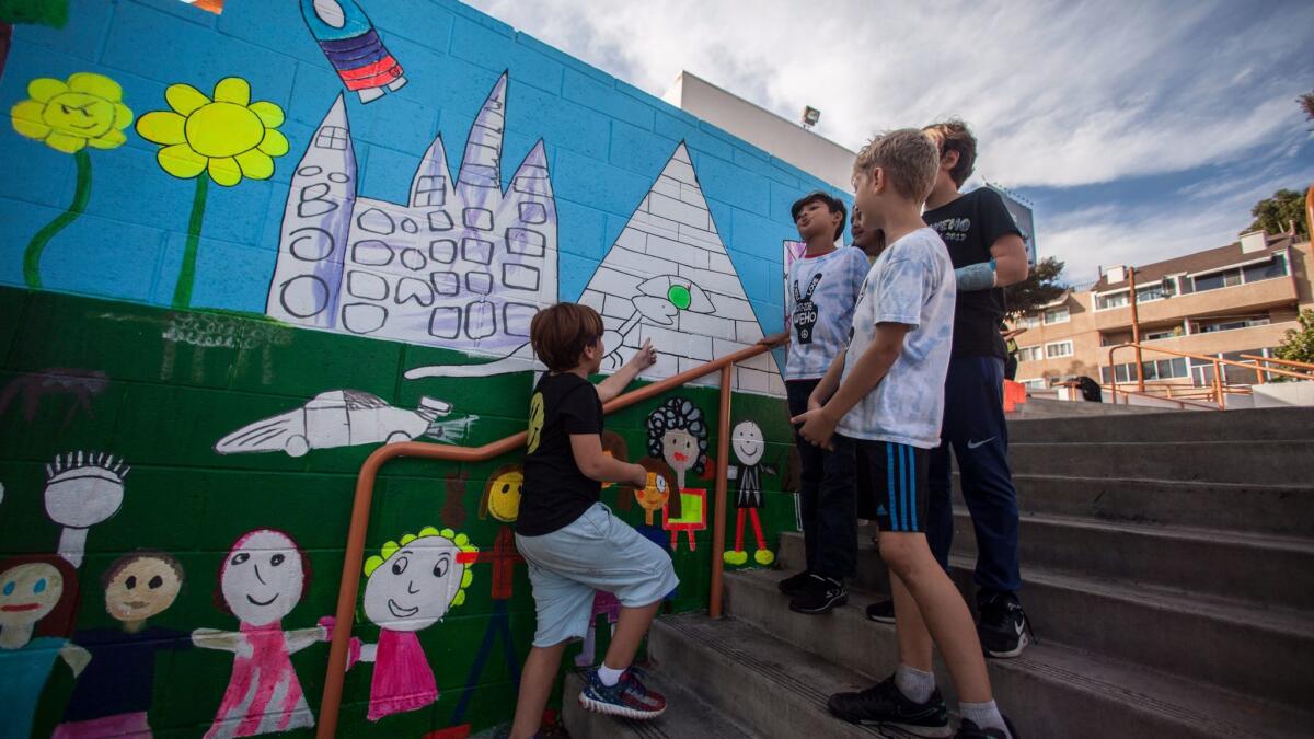 First-grader Sasha Susini, left, points to his favorite part of a new mural at West Hollywood Elementary School, a project of London-based Arts Club, which hopes to build an eight-story building nearby.