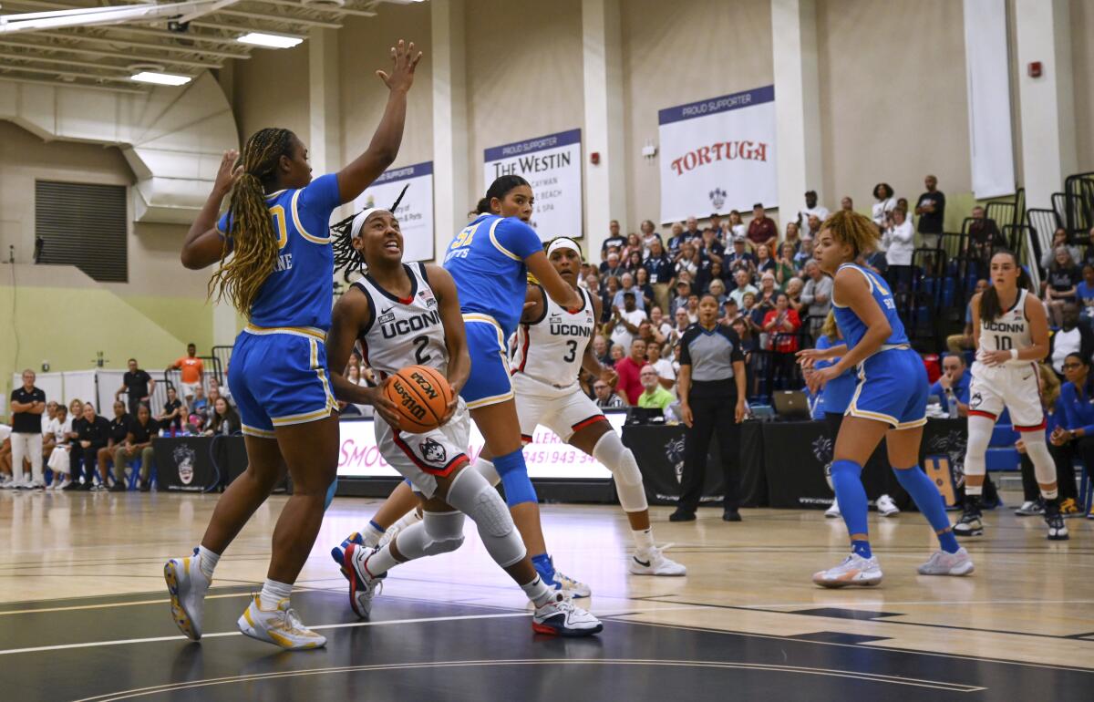 UConn's KK Arnold drives to the basket between UCLA's Charisma Osborne and Lauren Betts 