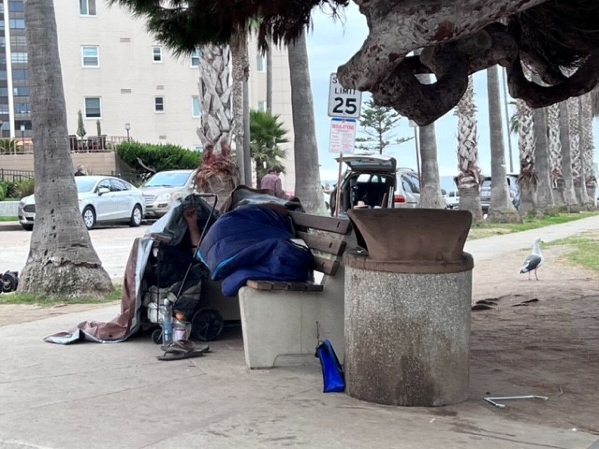 A homeless person sleeps on a bench at Girard Avenue and Coast Boulevard in La Jolla in October.