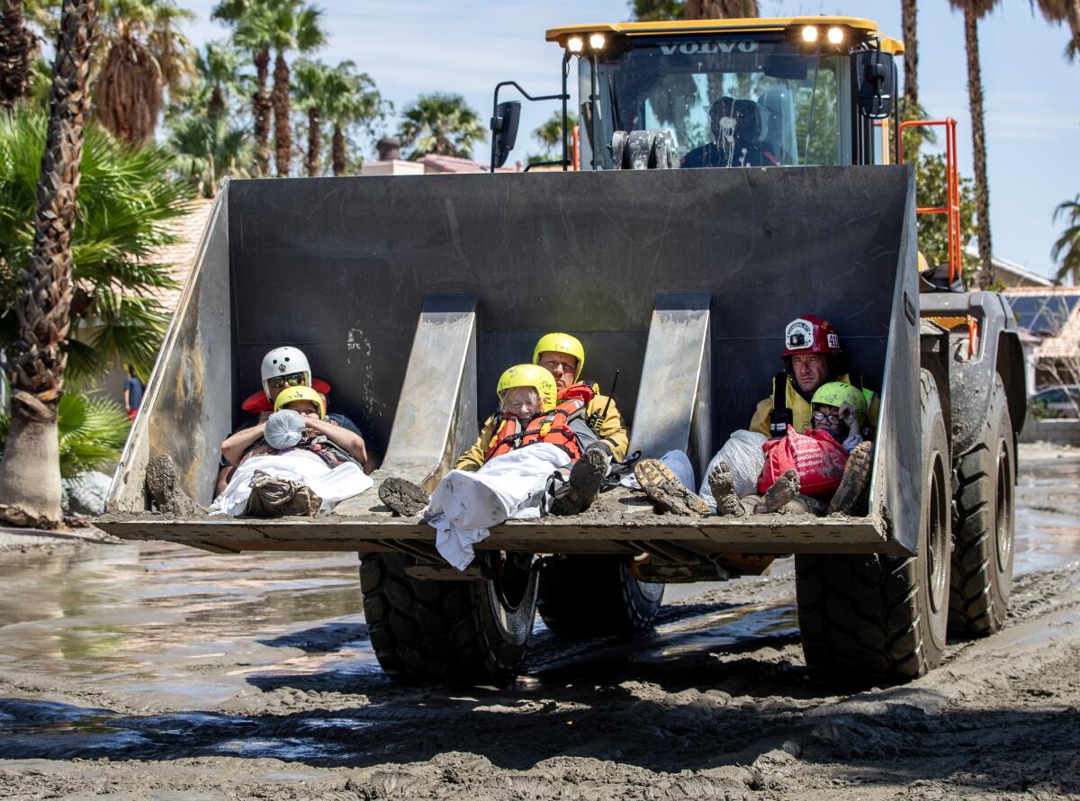 Residents from a senior living facility are held by firefighters in a front loader while being brought to safety.
