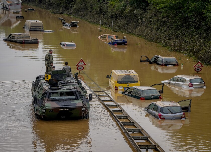 German soldiers check for victims in partially submerged cars on a flooded road