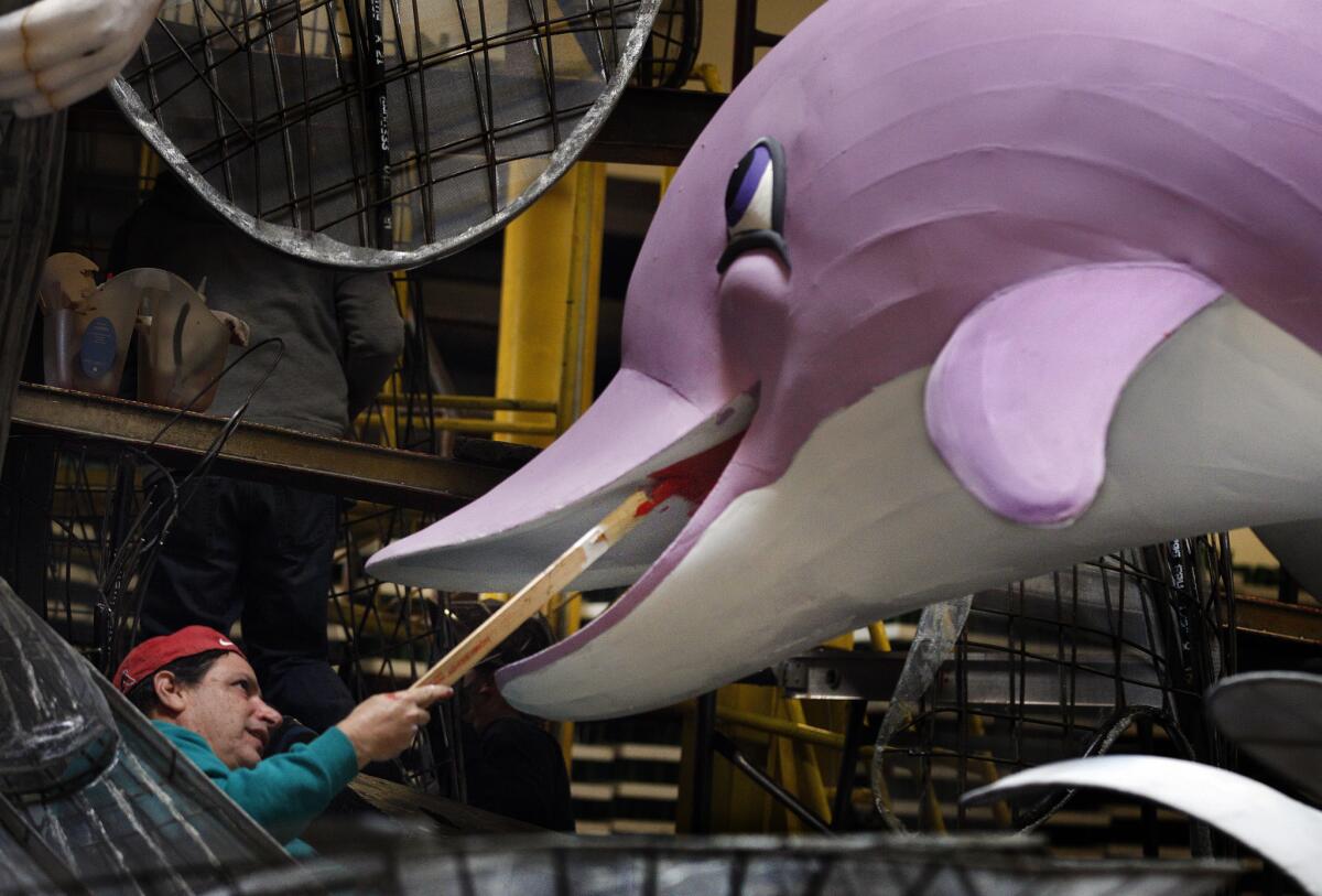 Artist Marcus Pollitz readies a dolphin on a float the 128th Rose Parade, which moves to Monday, Jan. 2, instead of New Year's Day, which falls on Sunday.