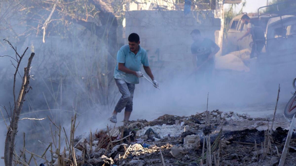 Syrians use dirt to put out a fire at the scene of a reported airstrike in the Jisr Shughur district of Idlib province on Sept. 4, 2018.