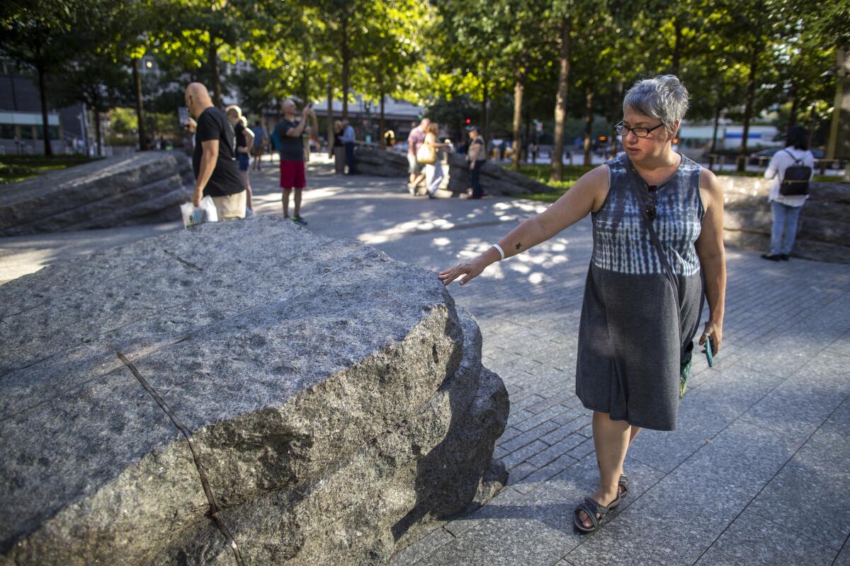 A visitor touches one of the granite slabs that recognize an initially unseen toll of the 9/11 terrorist attacks: firefighters, police and others who died or fell ill after exposure to toxic materials unleashed in the wreckage.