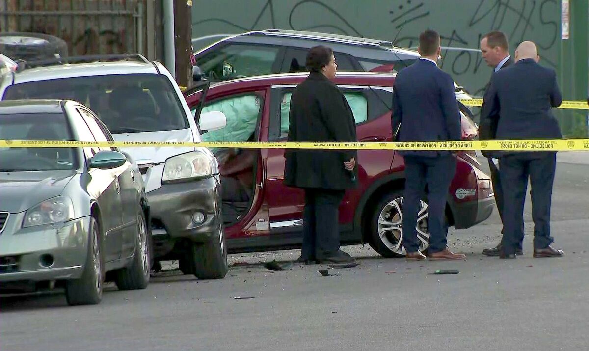 Investigators stand behind police tape at the scene of a car crash.
