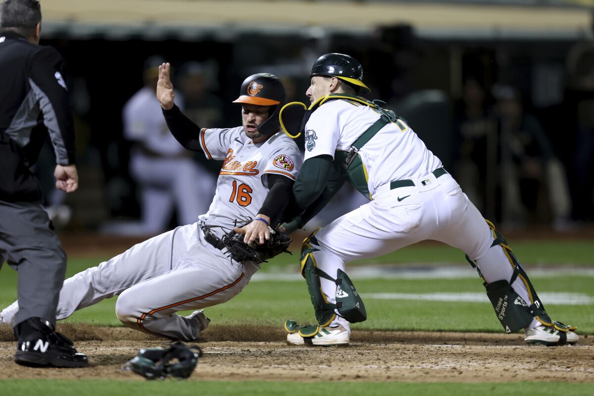 Baltimore Orioles' Trey Mancini (16) is tagged out at home by Oakland Athletics catcher Sean Murphy, right, on a ball hit by Austin Hays during the seventh inning of a baseball game in Oakland, Calif., Monday, April 18, 2022. (AP Photo/Jed Jacobsohn)