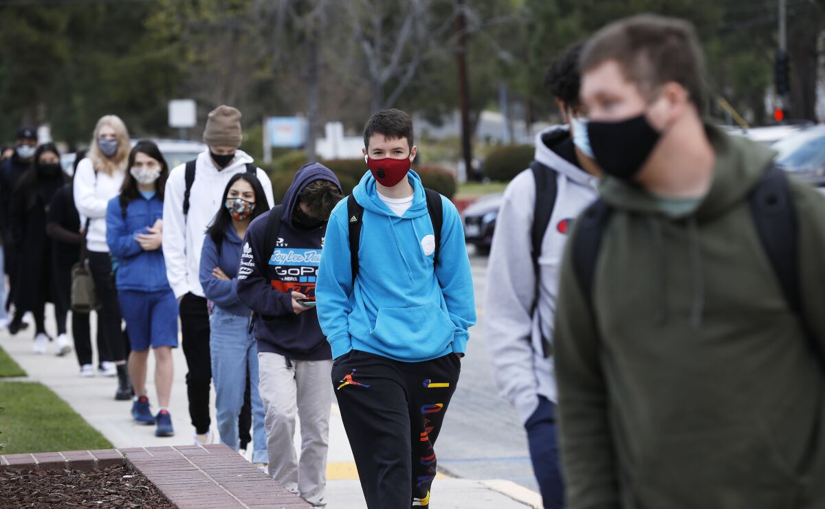 Young people with face masks line up.