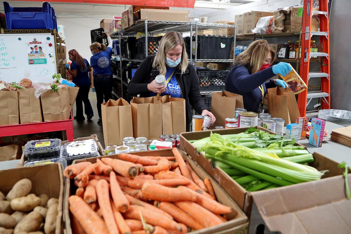 Volunteers with AAA Auto Club Enterprises help prepare food bags during a Thanksgiving food distribution event.