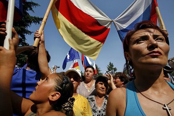 The flags of Russia and South Ossetia are linked at a rally in Tskhinvali. Moscow's top diplomat said 500 troops would remain at eight posts in Georgia proper, well outside South Ossetia, an enclave seeking independence from Georgia.