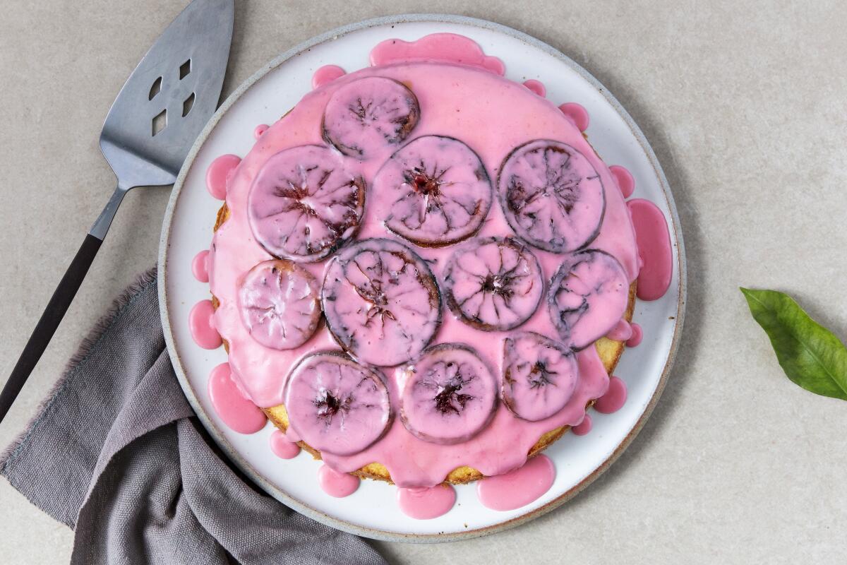 A round single-layer cake topped with pink icing and blood orange slices.