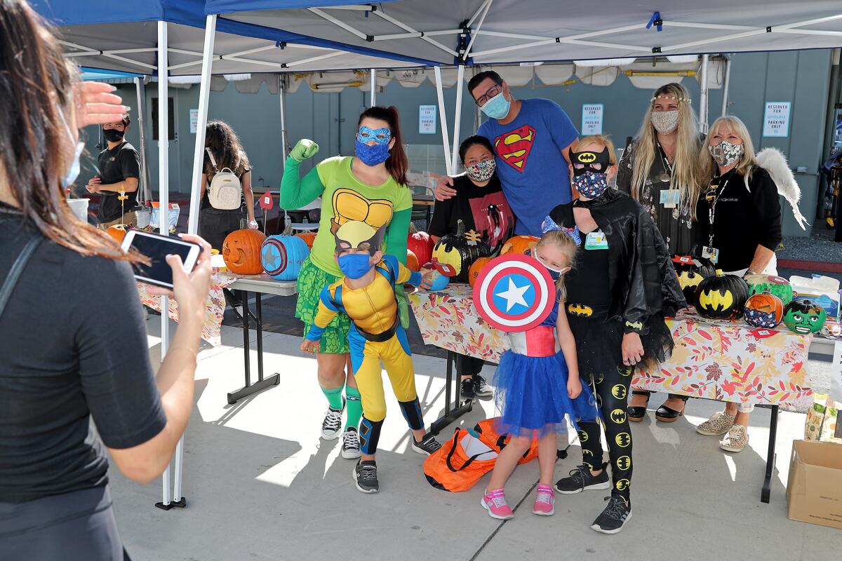 A mother and her two children dressed as Marvel Super Heroes pose with faculty and staff members.