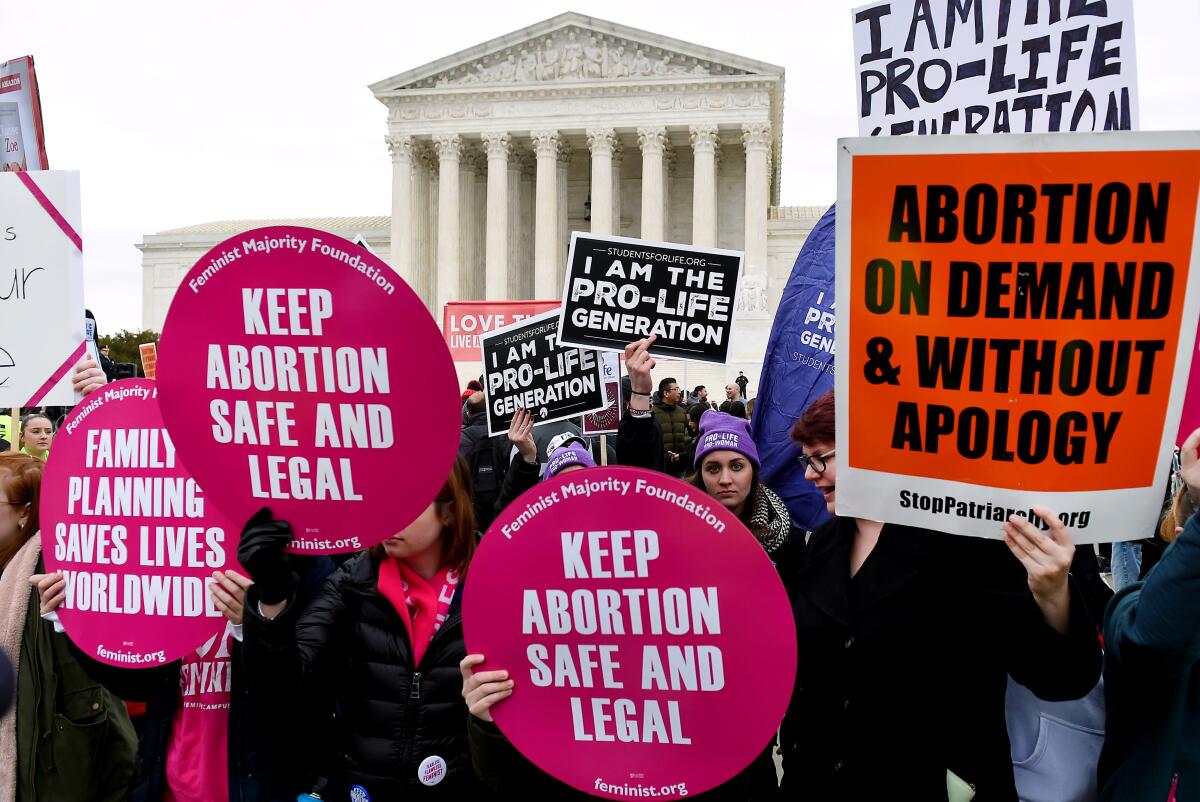 Demonstrators hold competing signs: "Keep abortion safe and legal, says one. Another, "I am the pro-life generation."