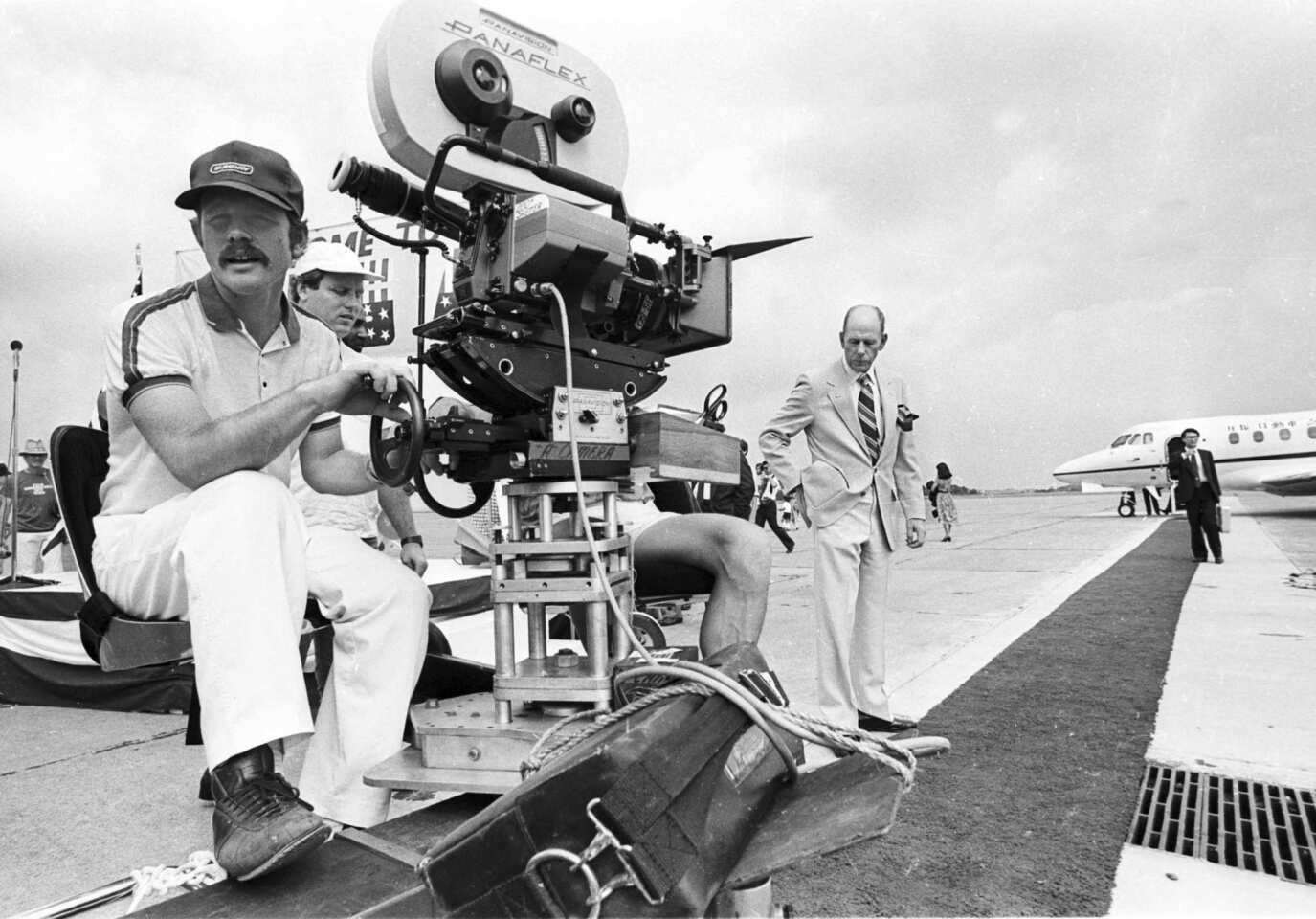Director Ron Howard takes a seat behind the camera during the production of his comedy "Gung Ho" while on location at the Allegheny County Airport near Duquesne, Pa., in August 1985. At right is his father, actor Rance Howard, who has a cameo.