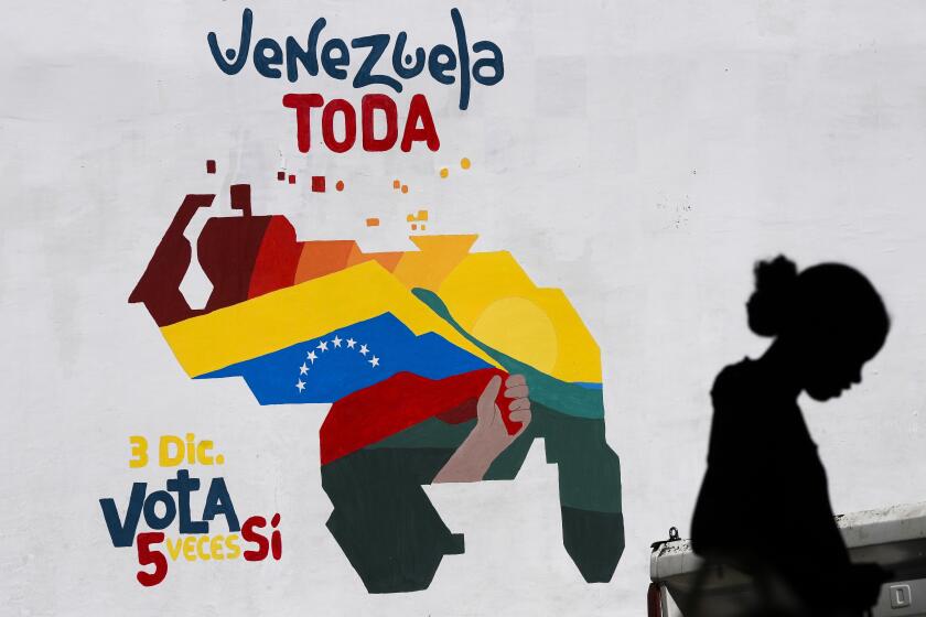 A woman sells fruit in front of a mural of the Venezuelan map with the Essequibo territory included, in Caracas, Venezuela, Wednesday, Nov. 29, 2023. Venezuelans will attempt to decide the future of the Essequibo territory, a large swath of land that is administered and controlled by Guyana but claimed by Venezuela, via a referendum that the Venezuelan government put forth in its latest attempt to claim ownership, saying it was stolen when a north-south border was drawn more than a century ago. (AP Photo/Matias Delacroix)