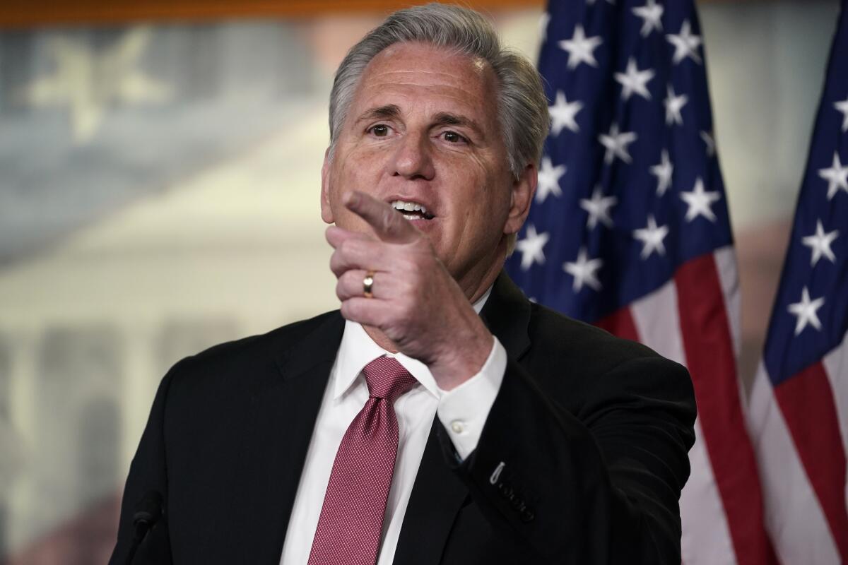 Kevin McCarthy points as he speaks in front of U.S. flags.