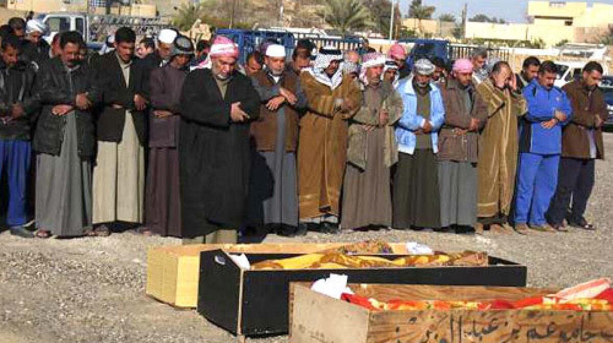 Men pray during the funeral of an Iraqi couple and their son killed when the U.S. military stormed their house, official said.