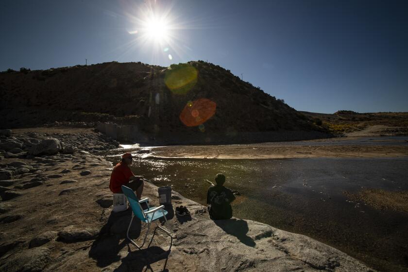 HESPERIA, CA - NOVEMBER 5, 2019: Victorville residents Charles Pritchett, left, and Kyle Carroll enjoy the solitude of the Mojave River just downstream from the Mojave River Dam on November 5, 2019 in Hesperia, California. Pritchett said he's been coming to this spot with his family for 30 years. Now, federal engineers have found that the Mojave River Dam falls short of national safety standards and could collapse in an extreme flowing event, inundating the high desert communities of Victorville, Hesperia, Apple Valley and Barstow.(Gina Ferazzi/Los AngelesTimes)
