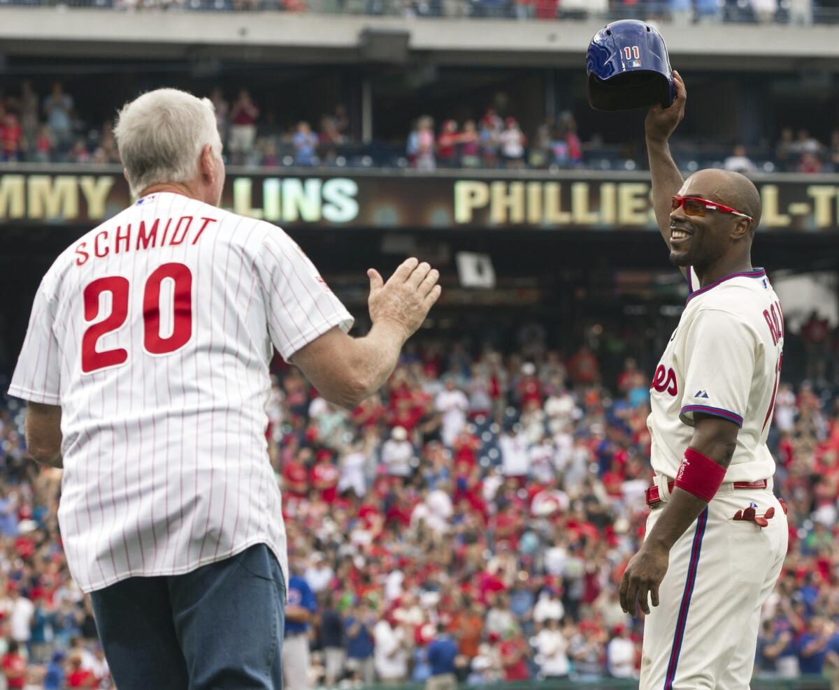 Jimmy Rollins raises his helmet to the crowd after passing Mike Schmidt, left, as the Phillies all time hit leader during the fifth inning of Philadelphia's 7-4 win Saturday over the Chicago Cubs.