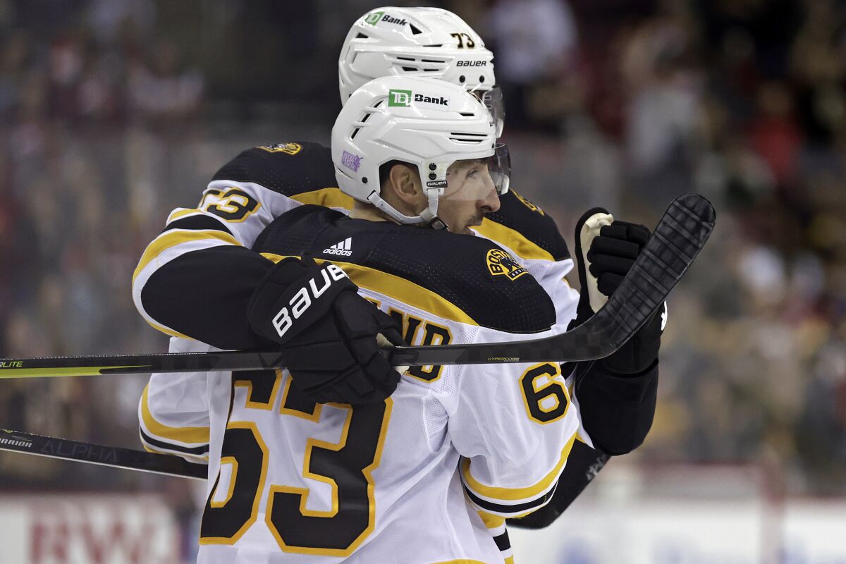 Boston Bruins center Brad Marchand (63) celebrates scoring a goal with Charlie McAvoy during the second period of an NHL hockey game against the New Jersey Devils on Saturday, Nov. 13, 2021, in Newark, N.J. (AP Photo/Adam Hunger)