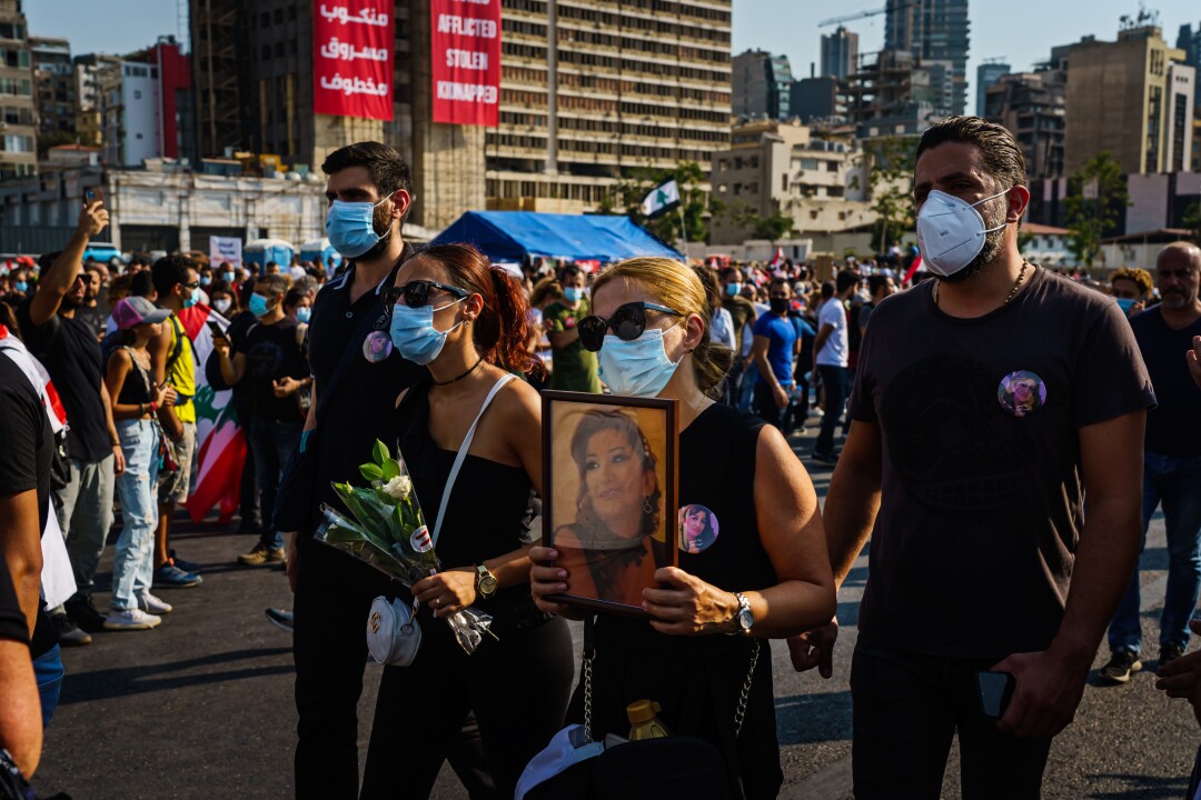 A woman, amid a rally, hold up a picture of a victim of the port explosion.