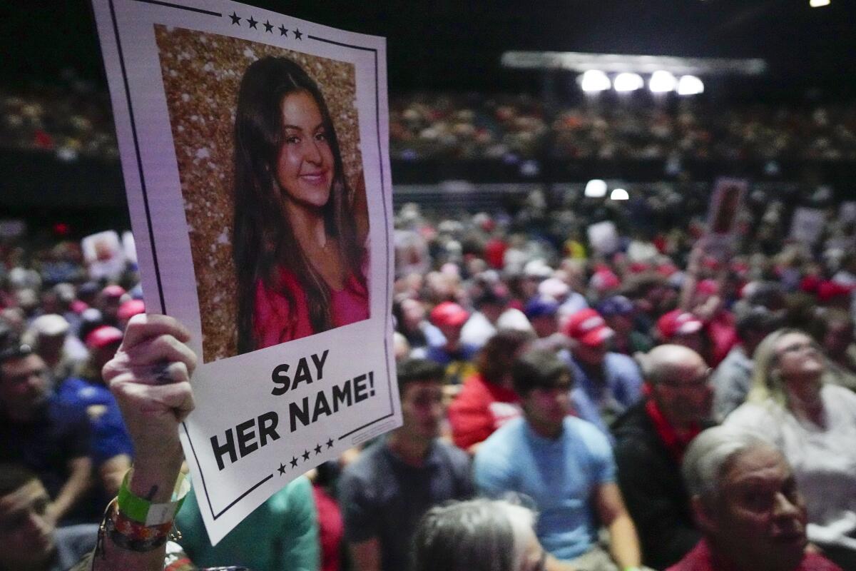A Trump supporter holds a poster with a photo of Laken Riley that reads "Say her name!"