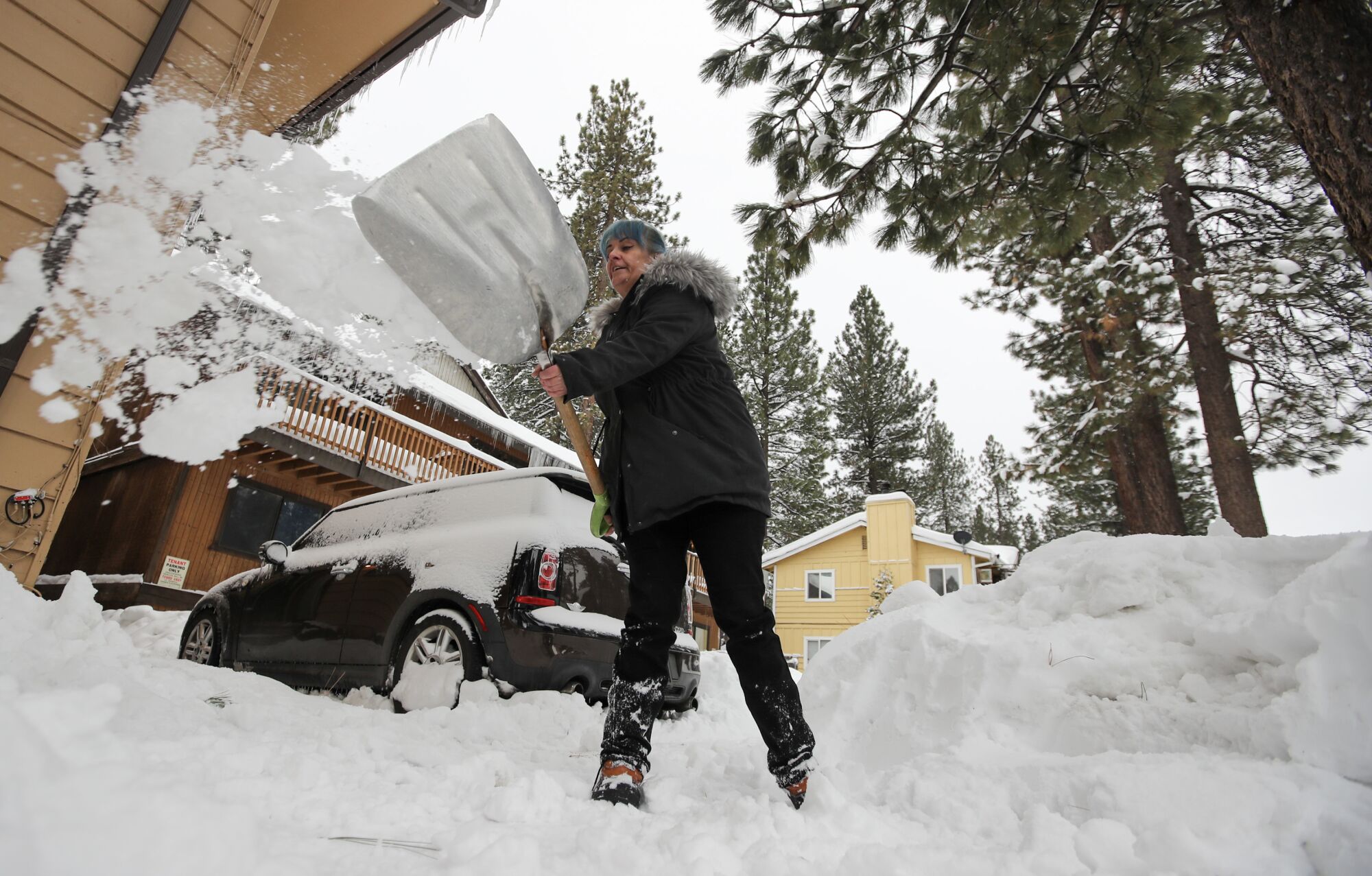 Amblerlee Barden shovels snow from her driveway after successive storms dumped several feet of snow in Big Bear.