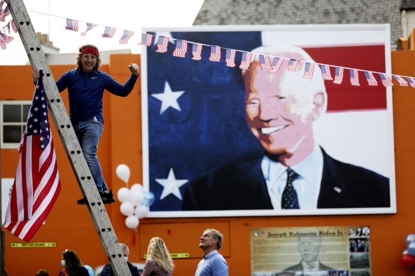 A man puts a US flag up in the town of Ballina, the ancestral home of President elect Joe Biden, in North West of Ireland, Saturday, Nov. 7, 2020. Biden was elected Saturday as the 46th president of the United States, defeating President Donald Trump in an election that played out against the backdrop of a pandemic, its economic fallout and a national reckoning on racism. (AP Photo/Peter Morrison)
