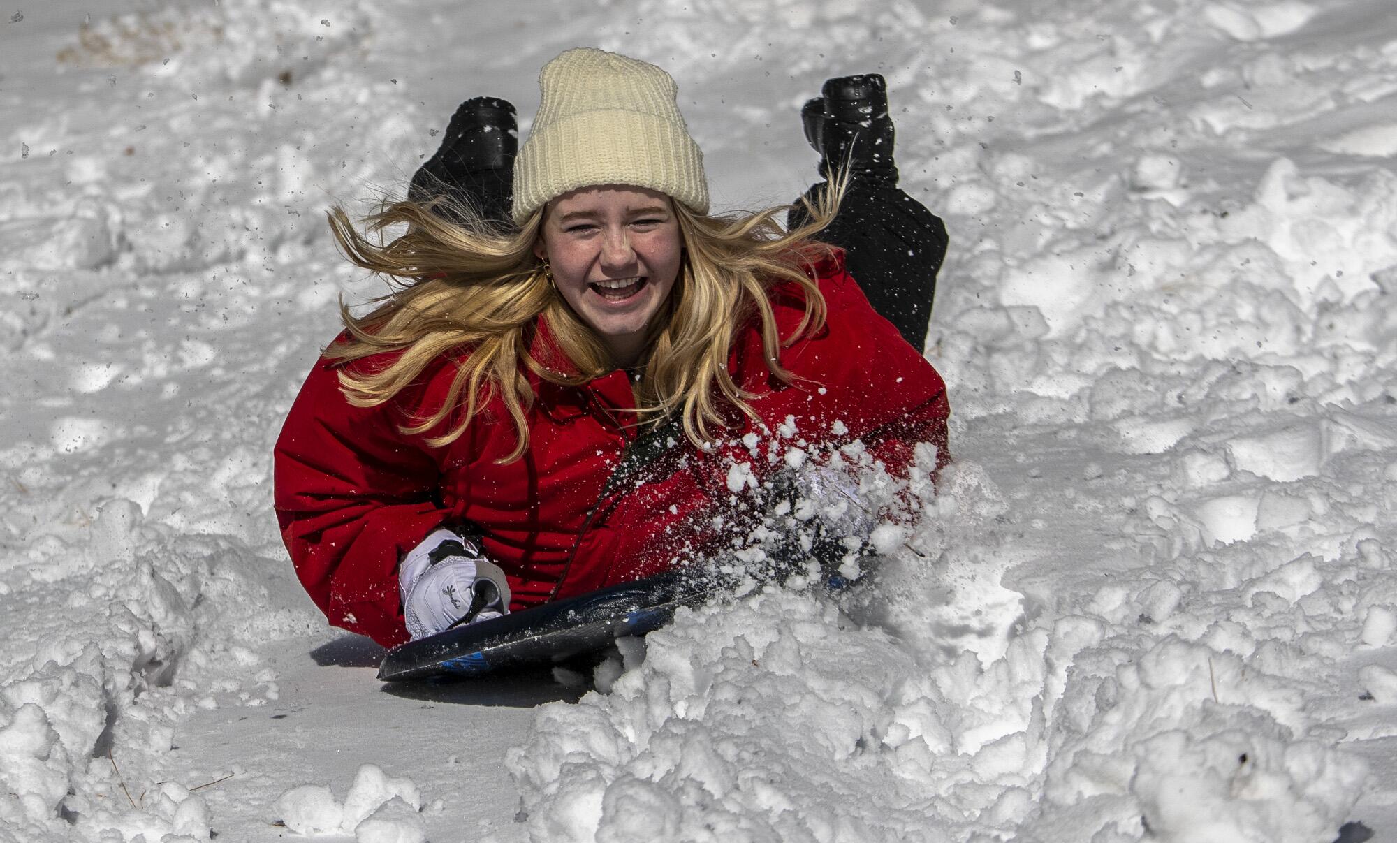Tina Lewis sleds belly down in fresh snow with her hair flying.