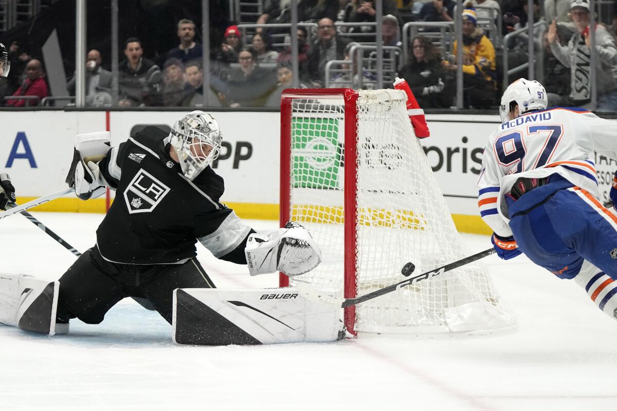 Kings goaltender Cam Talbot, left, reaches to stop a shot by Edmonton Oilers center Connor McDavid at Crypto.com Arena.