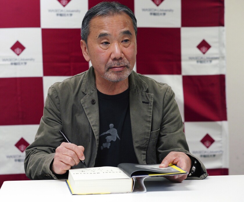 FILE - In this Nov. 3, 2018, file photo, Japanese novelist Haruki Murakami signs his autograph on his novel "Killing Commendatore" during a press conference in Tokyo. Murakami said politicians need to reduce public uncertainty and fear over the coronavirus by speaking sincerely about the pandemic. Murakami, in a two-hour live New Year's Eve show on Dec. 31, 2020, urged political leaders to “talk honestly from the gut” to the people to encourage them to help slow rising infections which are on the verge of getting out of control. (AP Photo/Eugene Hoshiko, File)