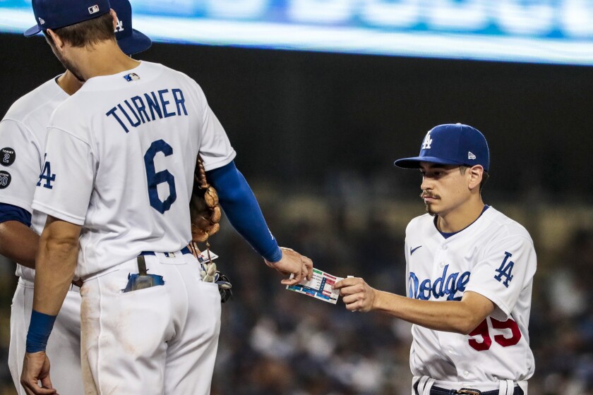 Dodgers bat boy Brandon Albert delivers new play cards to infielder Trea Turner during a pitching change