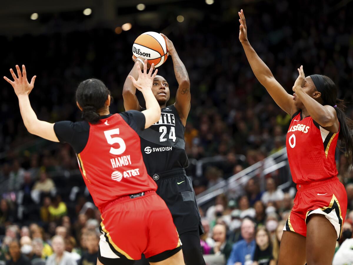 Seattle Storm guard Jewell Loyd (24) shoots between the defense of Las Vegas Aces forward Dearica Hamby (5) and guard Jackie Young (0) during the first half of Game 4 of a WNBA basketball playoff semifinal Tuesday, Sept. 6, 2022, in Seattle. (AP Photo/Lindsey Wasson)