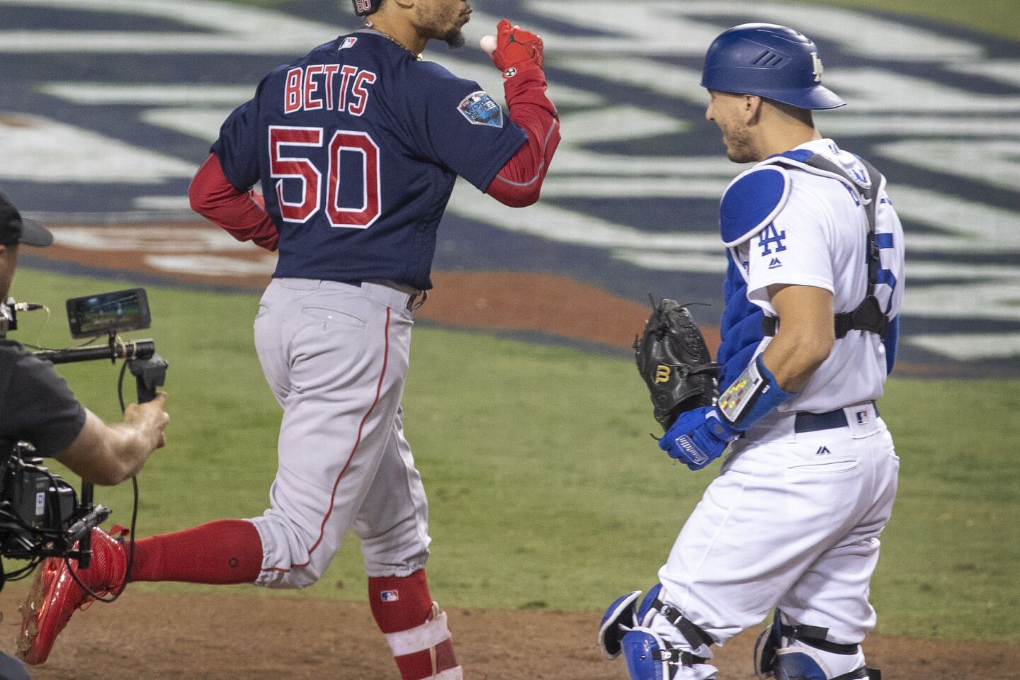 Dodgers catcher Austin Barnes looks away as Red Sox center fielder Mookie Betts celebrates after crossing home plate during his home-run trot in the sixth inning.