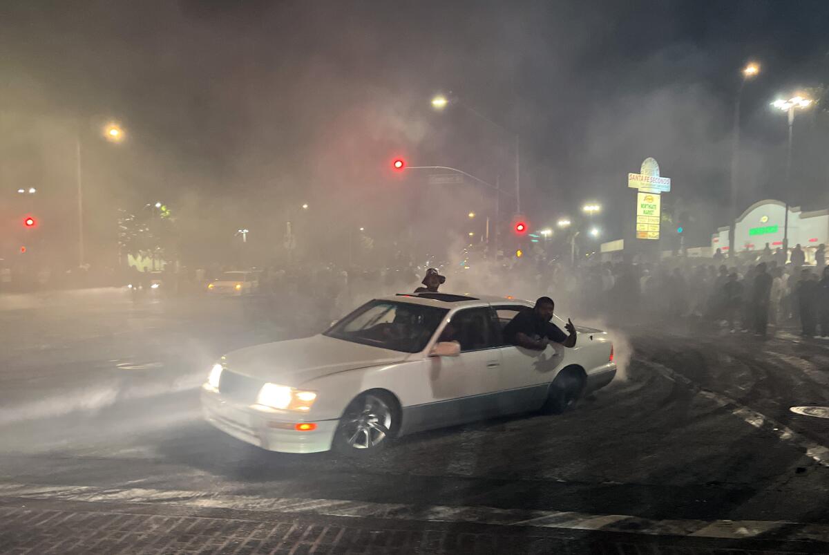 Passengers hang out of a spinning car at an early morning street takeover in East Compton.