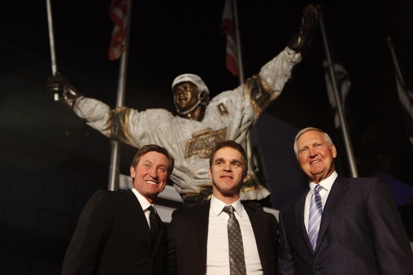 Kings hockey greats Wayne Gretzky, left, and Luc Robitaille, center, stand with Lakers legend Jerry West, right, in front of Robitaille's new bronze statue that was unveiled outside Staples Center.