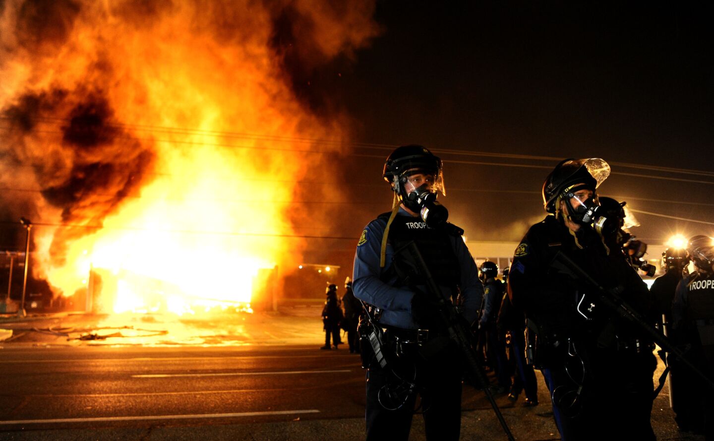 Police officers block West Florissant Avenue as a building burns in the background after a grand jury decision in Ferguson, Mo.