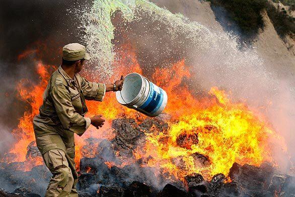 At a base outside Tijuana, a soldier hurls more fuel on a flaming heap of contraband drugs, including more than 2 tons of marijuana, cocaine, heroin and prescription pills. A steady breeze carried the smoke over other recruits training on a live-fire rifle range.