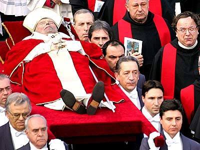 Pope John Paul II's body is carried across St. Peter's Square on its way to be placed in public viewing inside St. Peter's Basilica. Twelve pallbearers flanked by Swiss Guards carried the late pontiff's body on a crimson platform from the Sala Clementina, where it had laid in state since Sunday.