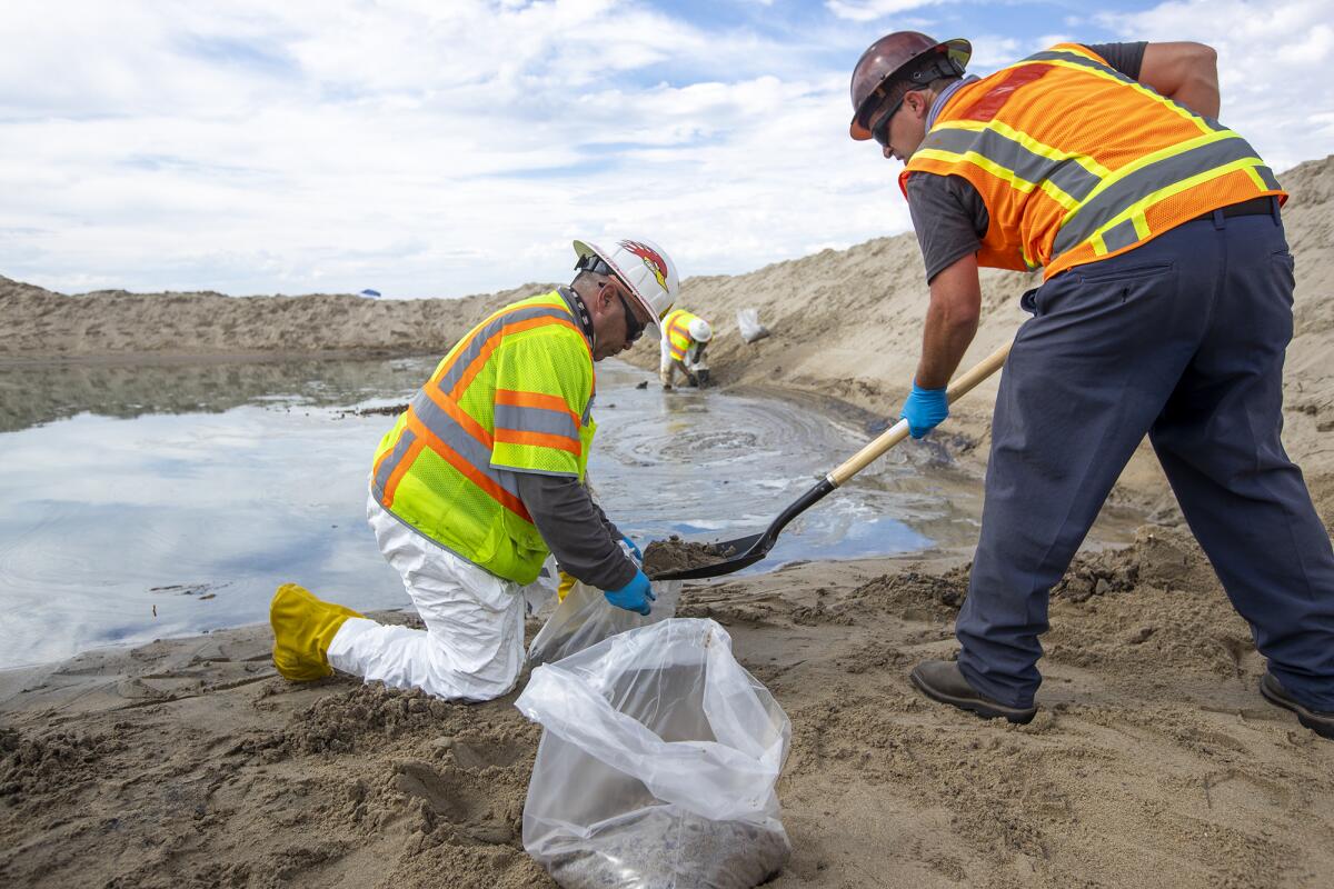 West Coast Environmental Solutions workers remove oil-laden sand Monday at the mouth of the Santa Ana River, October 4, 2021.