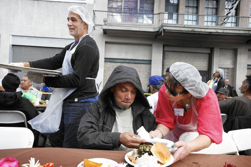 Gail Modyman serves Hector Diaz during the annual Midnight Mission Thanksgiving brunch on skid row.
