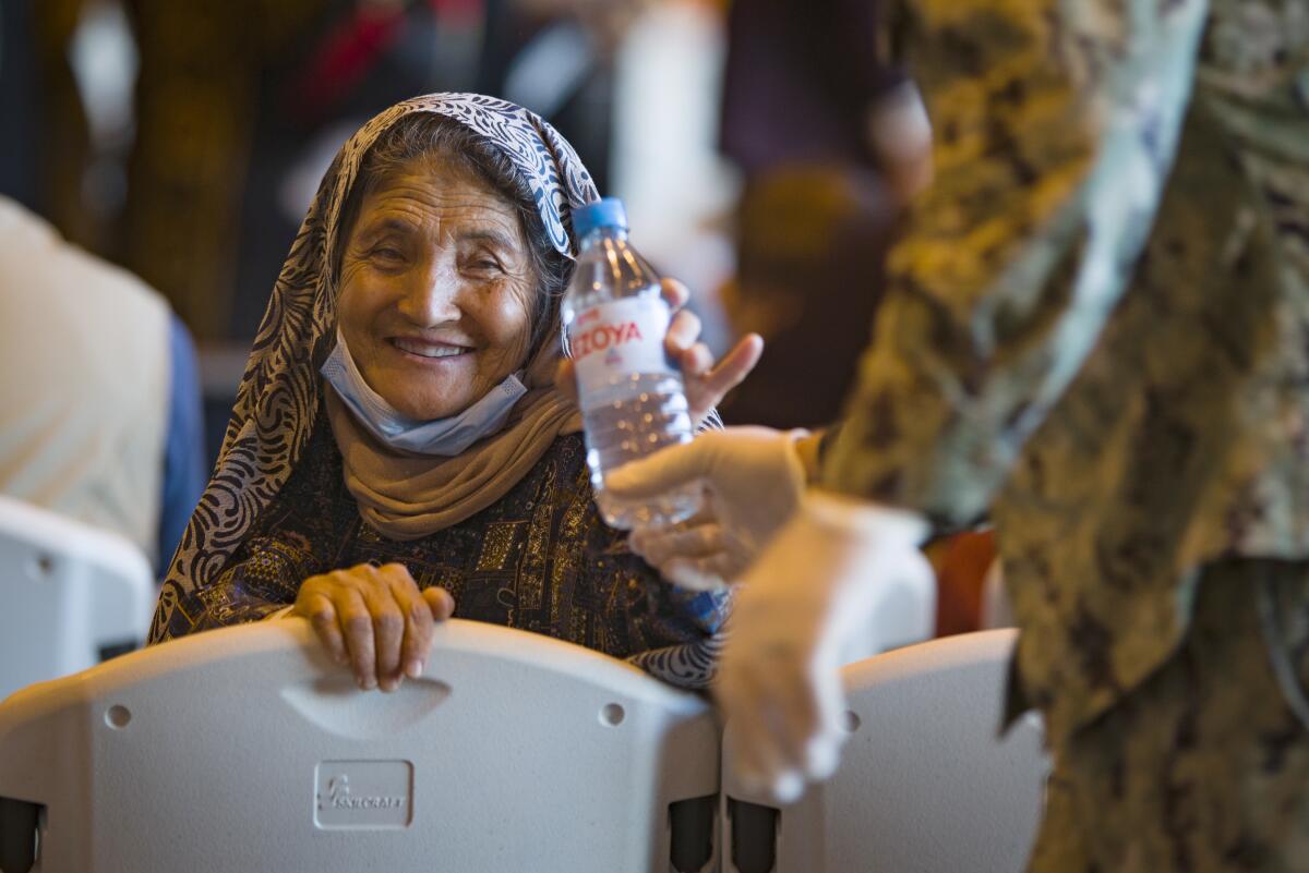 A woman holds a bottle of water and smiles.