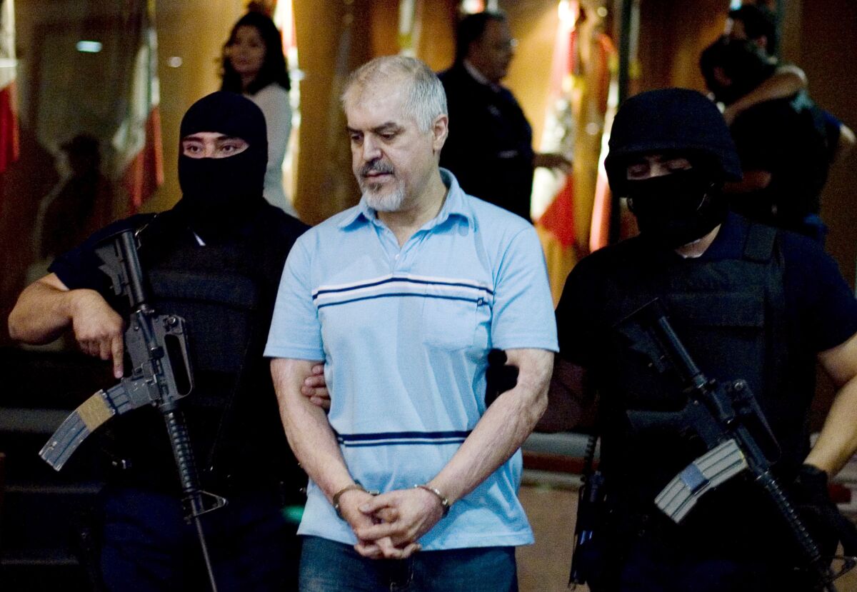 Eduardo Arellano Felix, also known as "The Doctor," center, is escorted by masked police officers in Mexico