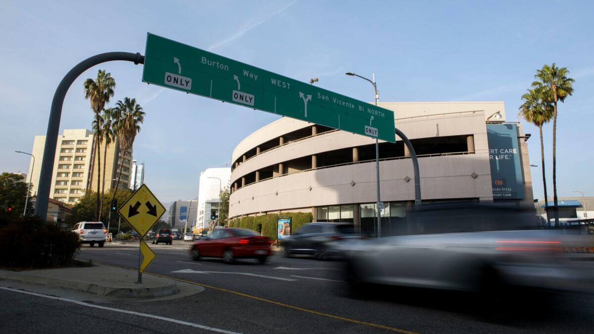 Cars drive past the proposed development site of 333 S. La Cienega Blvd., across from the Westbury Terrace condominium building, rear left, at the intersection of San Vicente and La Cienega boulevards.