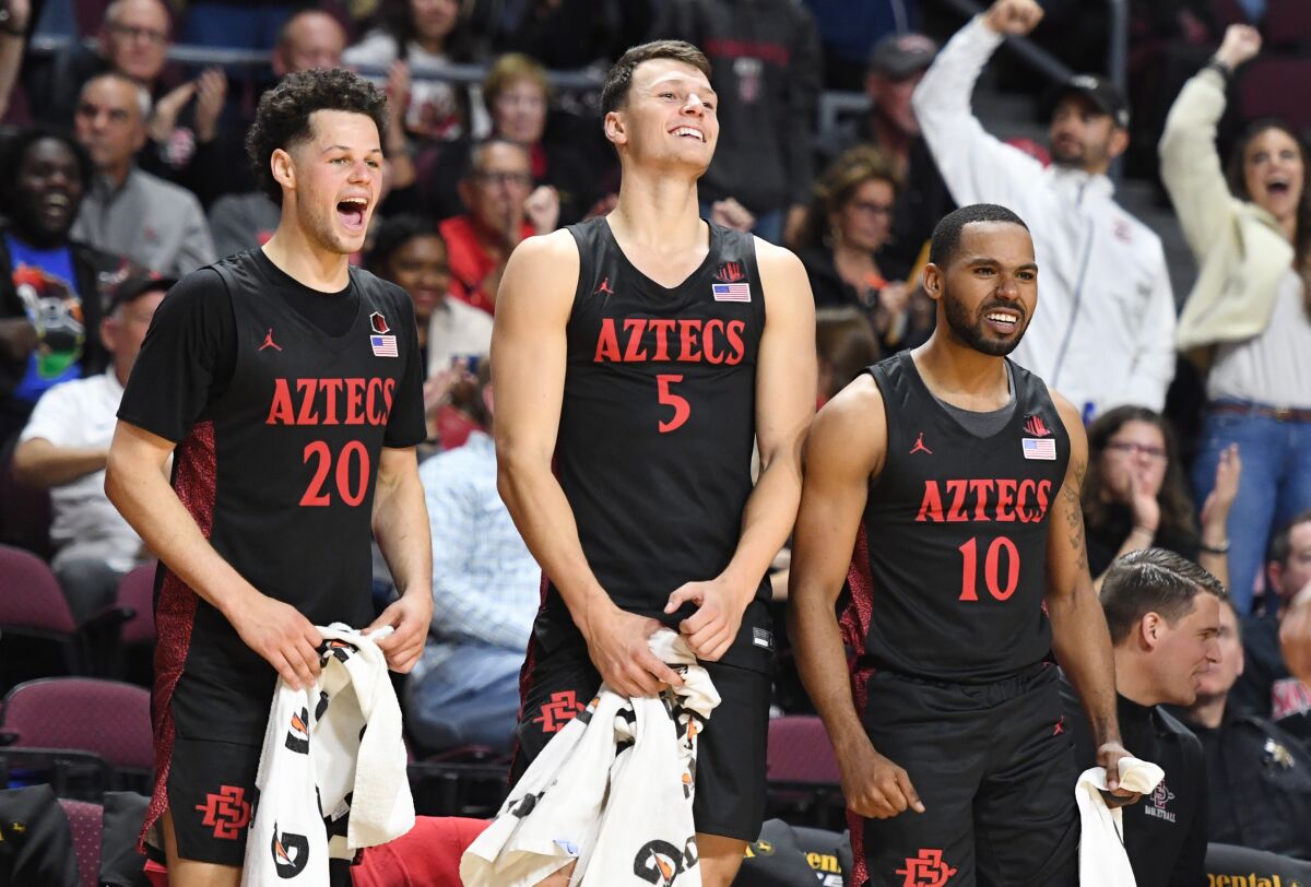 San Diego State players, from left, Jordan Schakel, Yanni Wetzell and KJ Feagin celebrate a teammate's dunk during a tournament game Nov. 28 in Las Vegas.