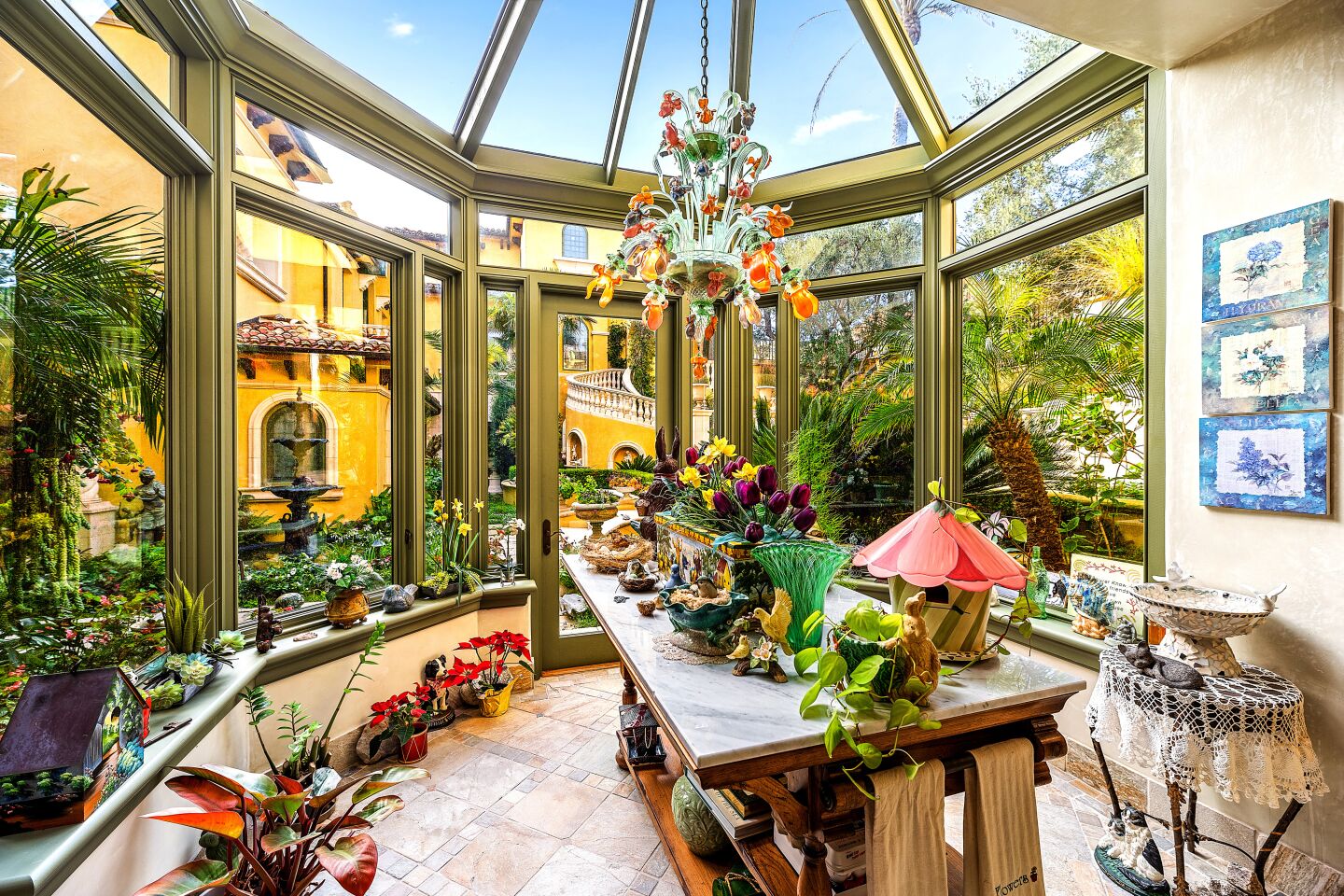 Plants fill a room with glass walls and ceiling.