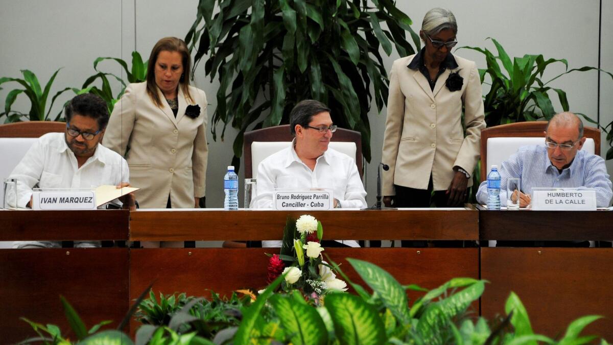 FARC commander Ivan Marquez, left, and Humberto de la Calle, head of the Colombian delegation for peace talks, sign a new agreement Saturday in Havana as Cuban Foreign Affairs Minister Bruno Rodriguez Parrilla looks on.