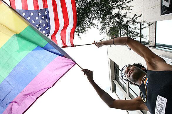 Edward Williams, 24, waves the American flag and a rainbow gay pride flag during the annual L.A. Pride parade in West Hollywood.